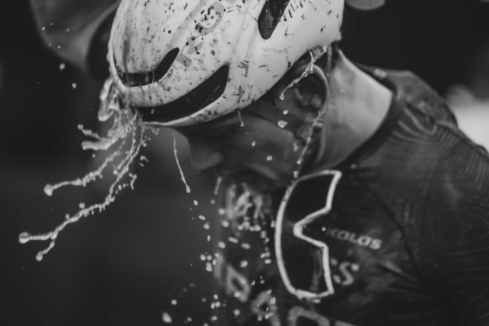 A rider drenched in water and mud, black and white