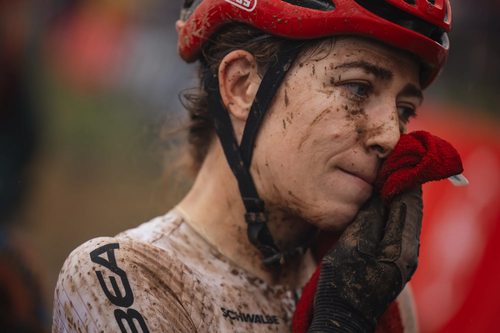 A rider wiping mud from their face with a towel