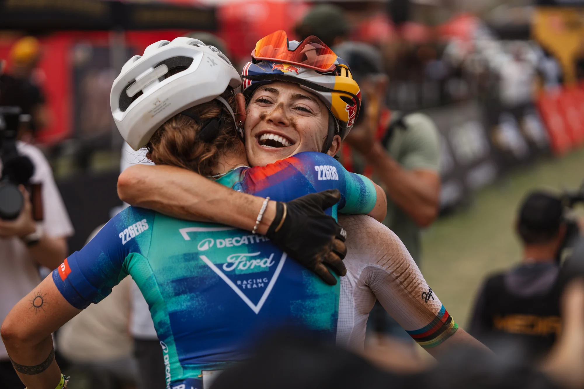 Two riders embracing, colourful jerseys