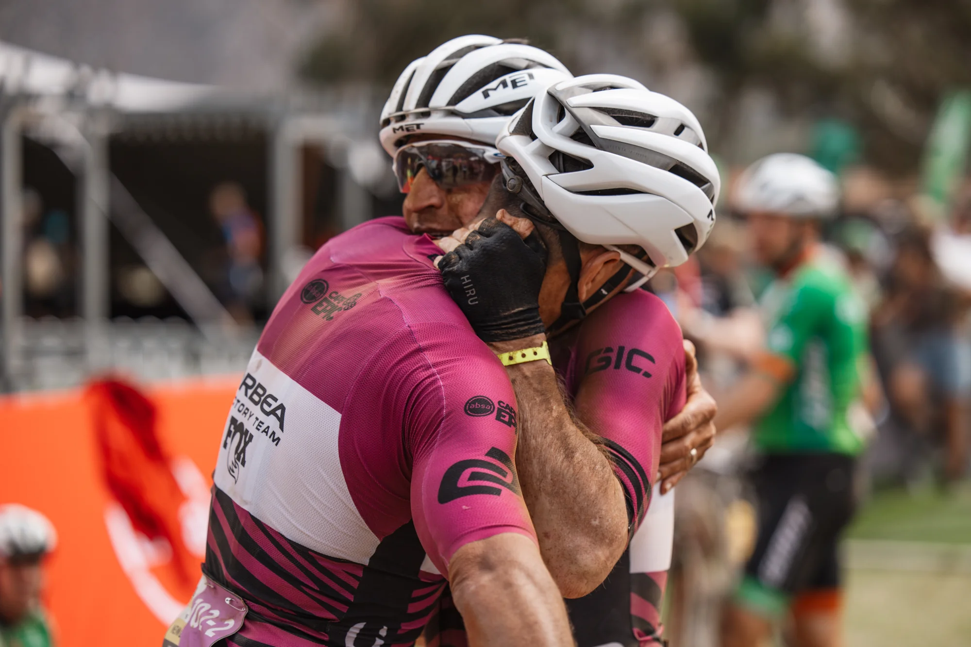 Two riders embracing, muddy