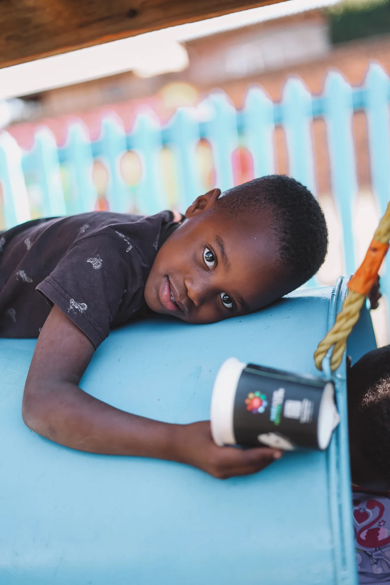 A child lying down, holding a mug