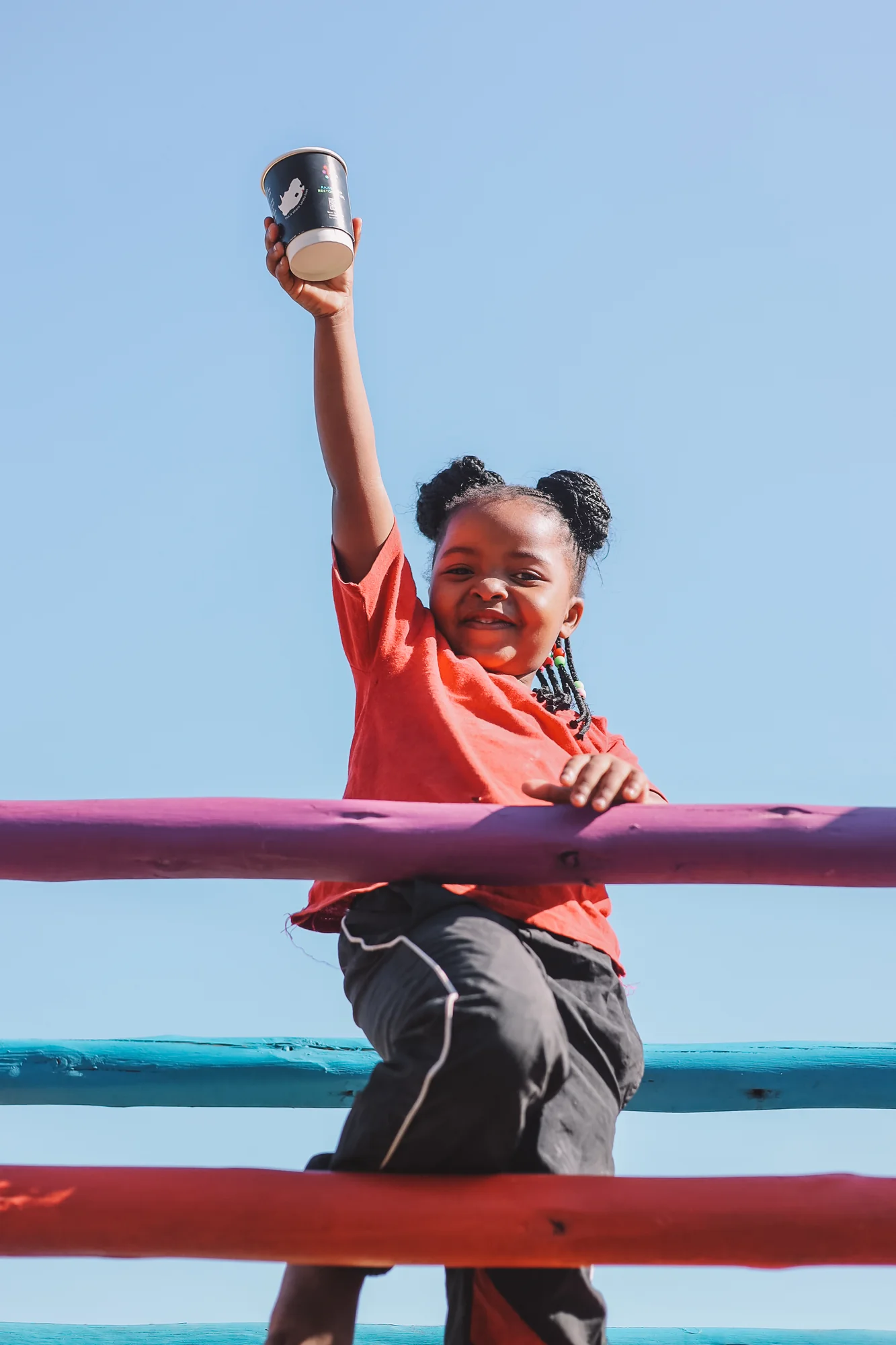 A child's portrait, mug raised, blue sky