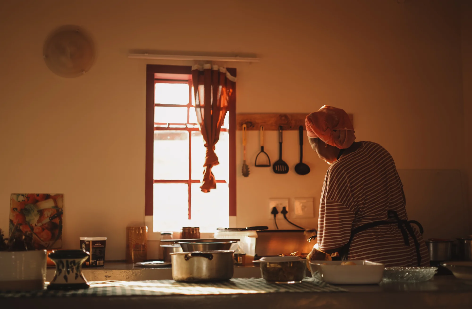 An adult cooking in a kitchen, warm light