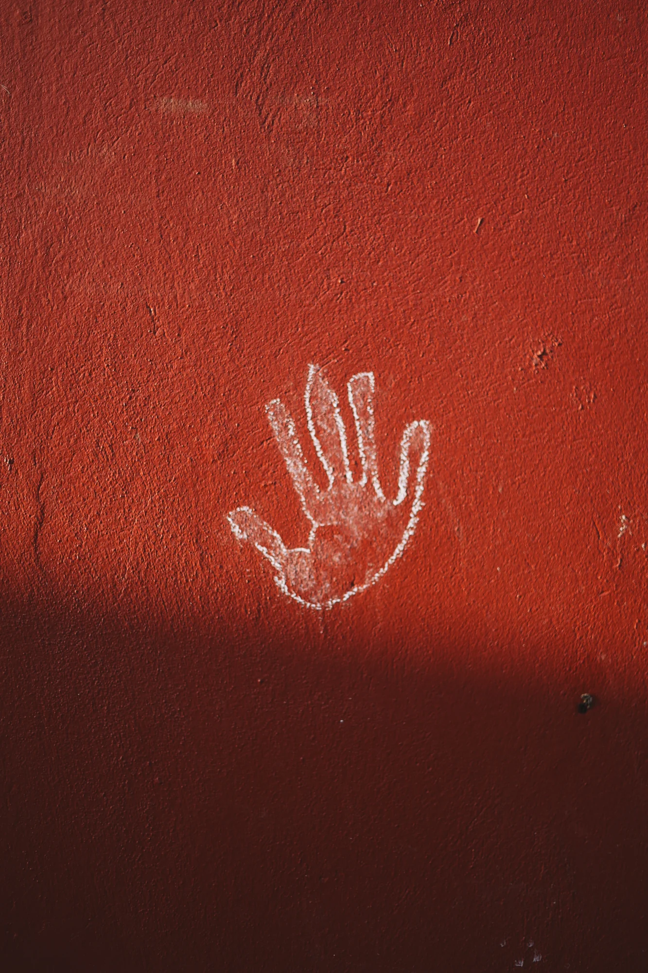 A white handprint on a red wall