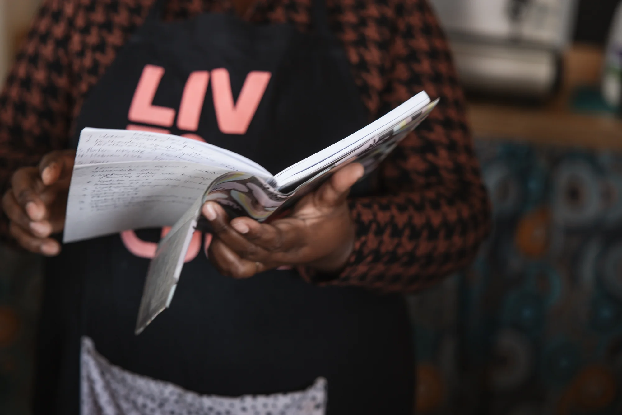 A woman reading notes, 'Liv' branded shirt