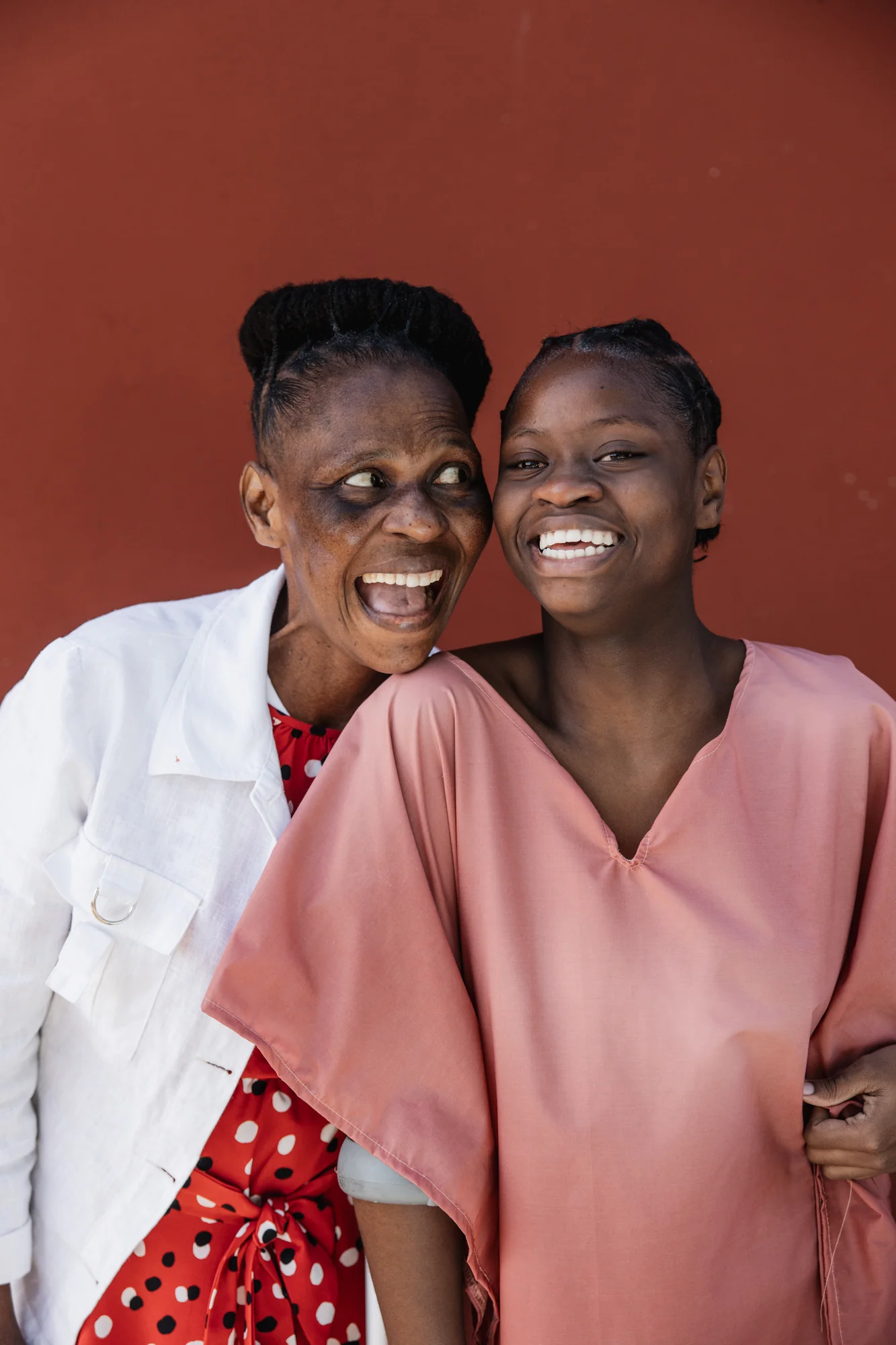A mother and daughter laughing together, red backdrop