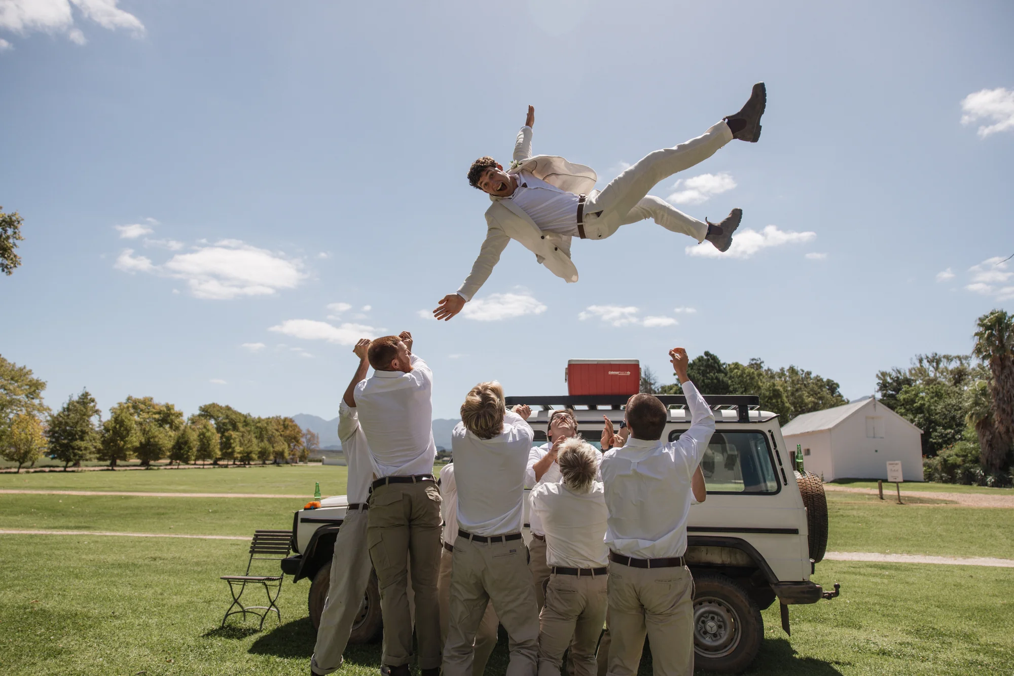 A groomsman mid-backflip off the Land Rover