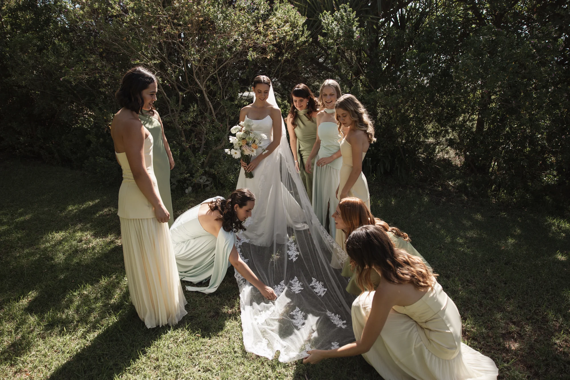The bridesmaids adjusting the veil, kneeling