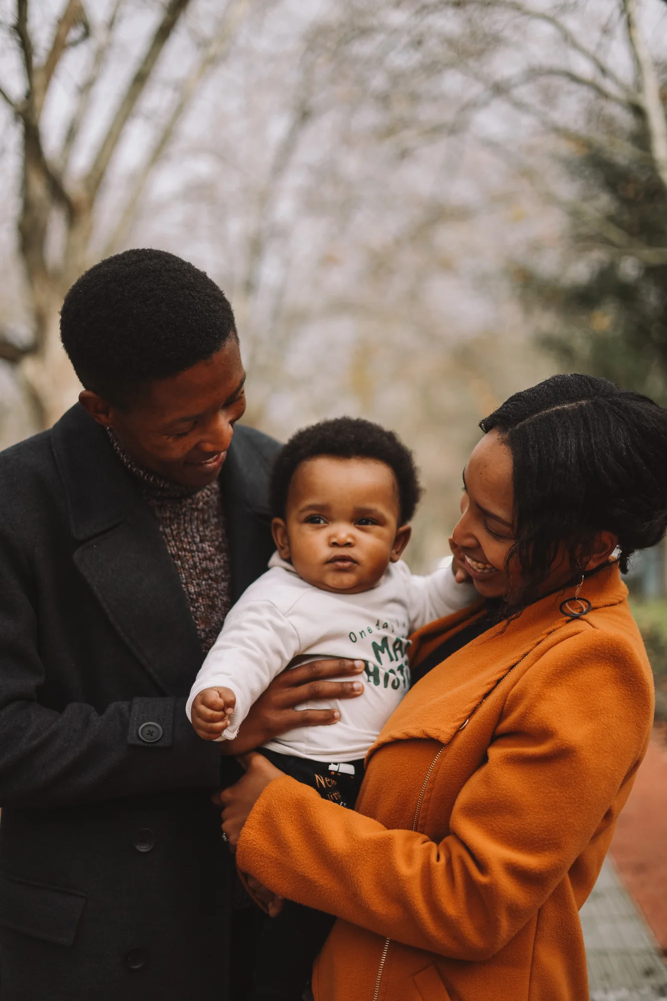 Godfrey and Boitumelo Mmagawo stand together with their son on a tree-lined path.