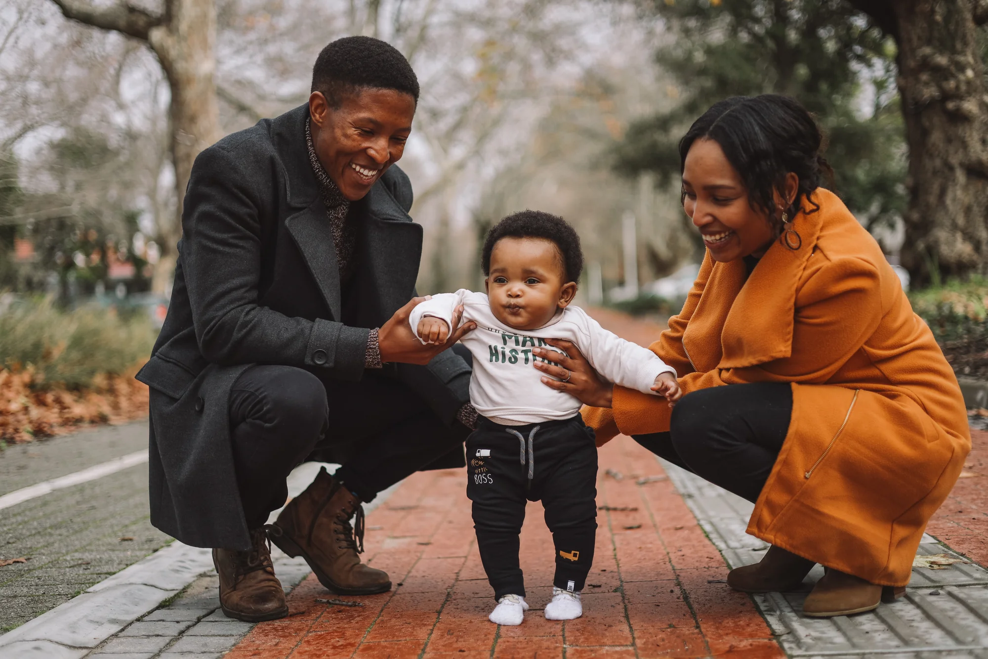 Godfrey and Boitumelo Mmagawo crouch on either side of their son as he takes a few steps.